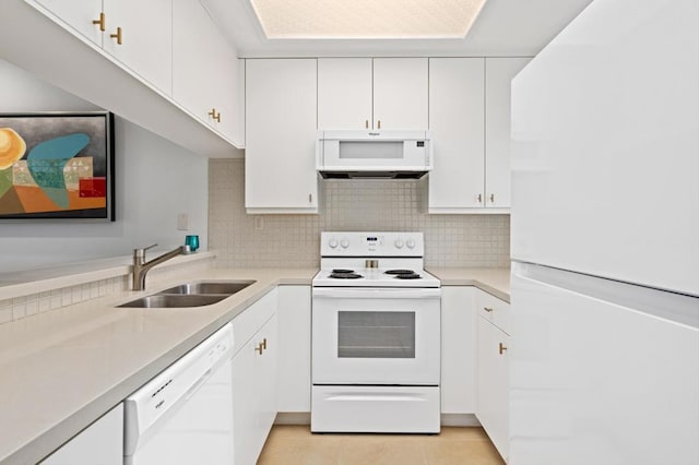 kitchen featuring white appliances, backsplash, sink, light tile patterned floors, and white cabinetry