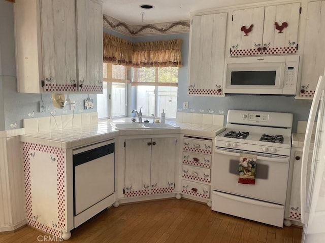 kitchen featuring white appliances, light hardwood / wood-style flooring, tile counters, and sink