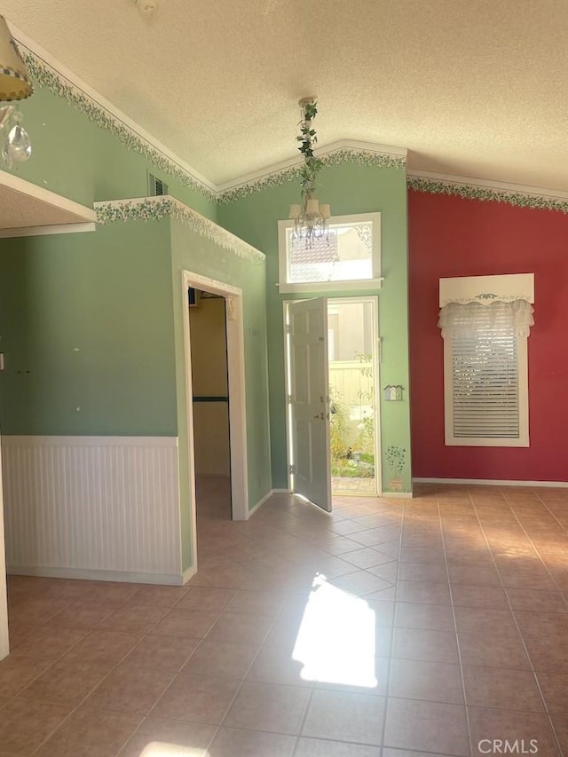 entrance foyer featuring tile patterned floors, lofted ceiling, a textured ceiling, and an inviting chandelier