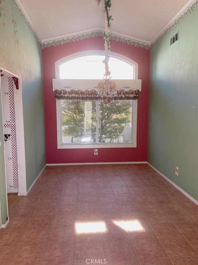 tiled spare room with plenty of natural light, lofted ceiling, ornamental molding, and a chandelier