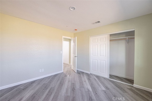 unfurnished bedroom with light wood-type flooring and a closet