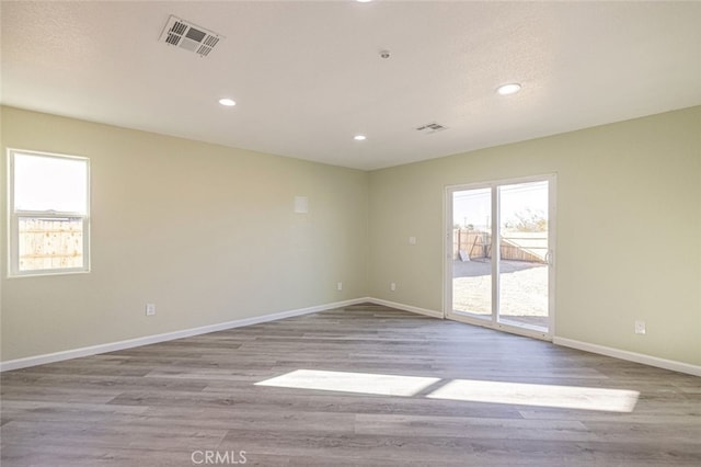 empty room with light hardwood / wood-style flooring and a textured ceiling