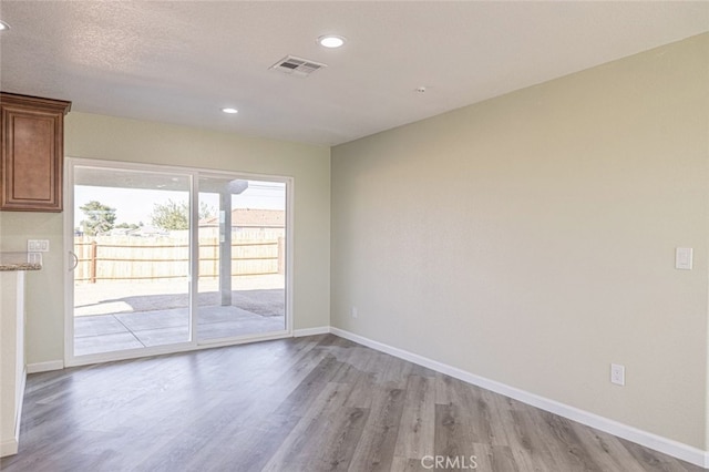 unfurnished room featuring a textured ceiling and light wood-type flooring