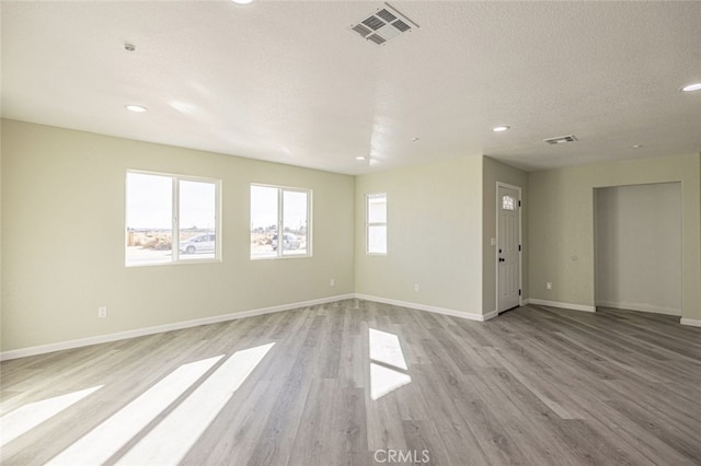 spare room featuring a textured ceiling and light hardwood / wood-style flooring