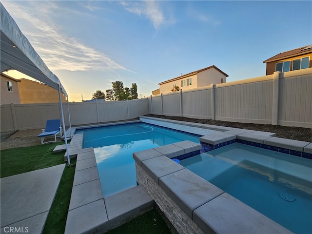 pool at dusk with an in ground hot tub