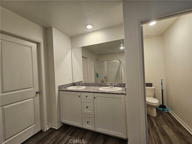 bathroom featuring vanity, a shower with shower door, hardwood / wood-style flooring, and toilet