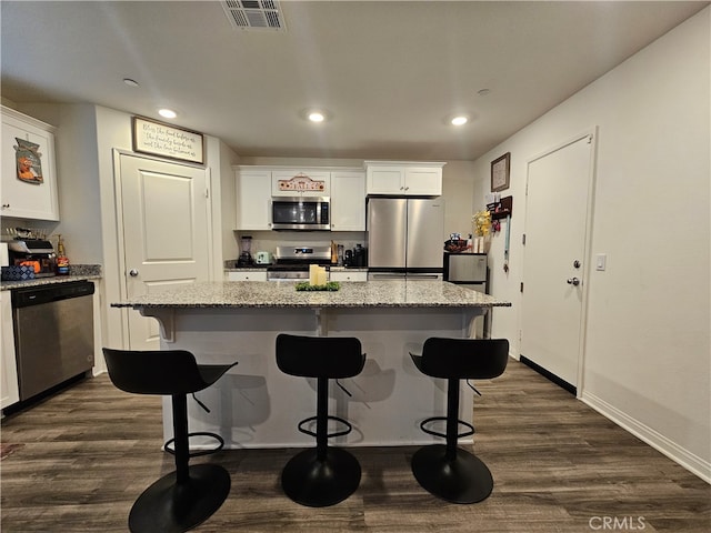 kitchen featuring white cabinets, light stone countertops, stainless steel appliances, and a kitchen island