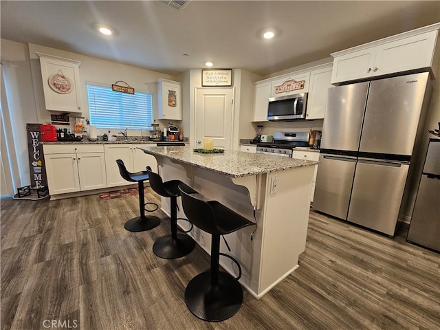 kitchen featuring a center island, white cabinetry, stainless steel appliances, and dark wood-type flooring