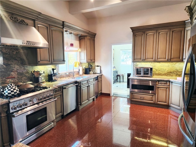 kitchen featuring light stone countertops, appliances with stainless steel finishes, sink, backsplash, and wall chimney exhaust hood