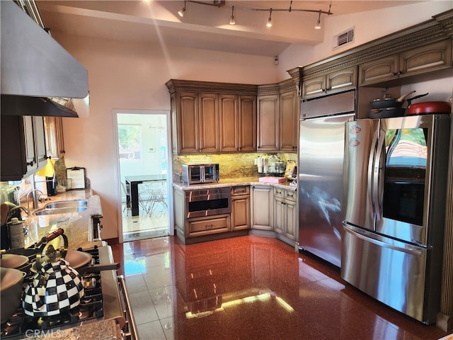 kitchen with decorative backsplash, exhaust hood, built in fridge, sink, and stainless steel fridge with ice dispenser