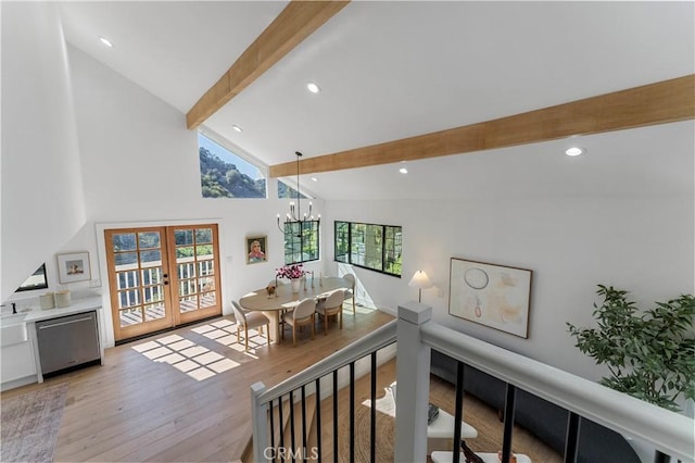 hallway with beam ceiling, french doors, an inviting chandelier, high vaulted ceiling, and light wood-type flooring