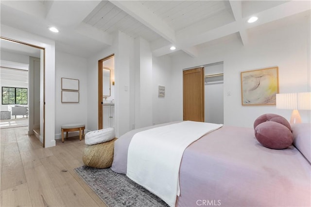 bedroom with light hardwood / wood-style floors, beam ceiling, and a closet