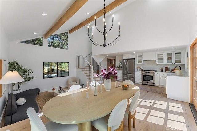 dining area with high vaulted ceiling, sink, light hardwood / wood-style flooring, beamed ceiling, and a notable chandelier