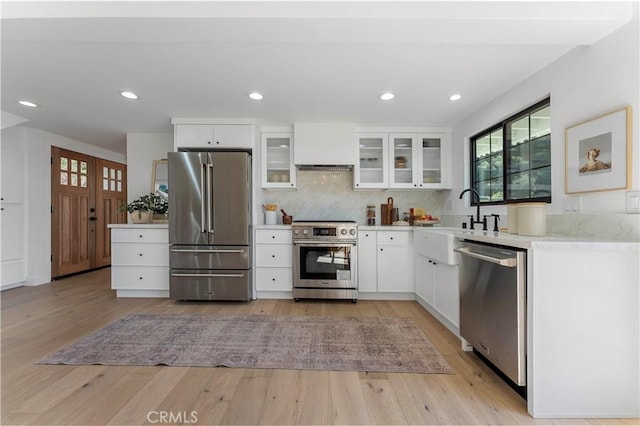 kitchen with light hardwood / wood-style floors, high quality appliances, white cabinetry, and sink