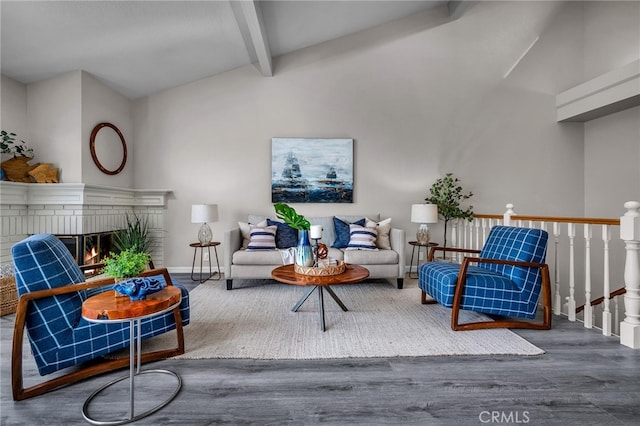 living room with hardwood / wood-style flooring, vaulted ceiling with beams, and a fireplace