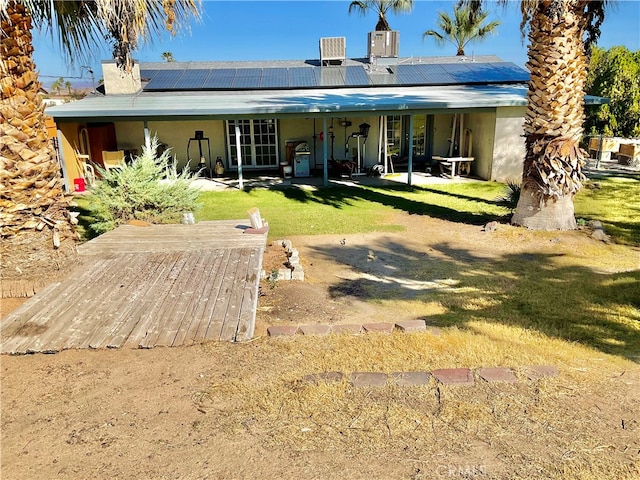 back of property featuring cooling unit, a patio area, solar panels, and a lawn