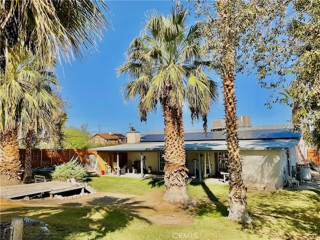 rear view of property featuring a yard and solar panels