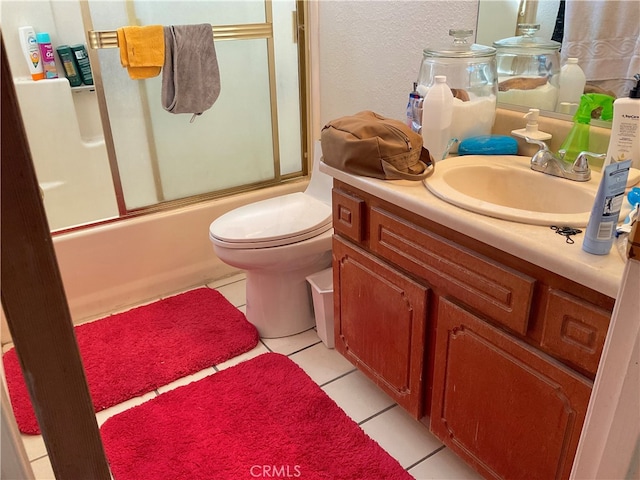 full bathroom featuring vanity, bath / shower combo with glass door, toilet, and tile patterned floors