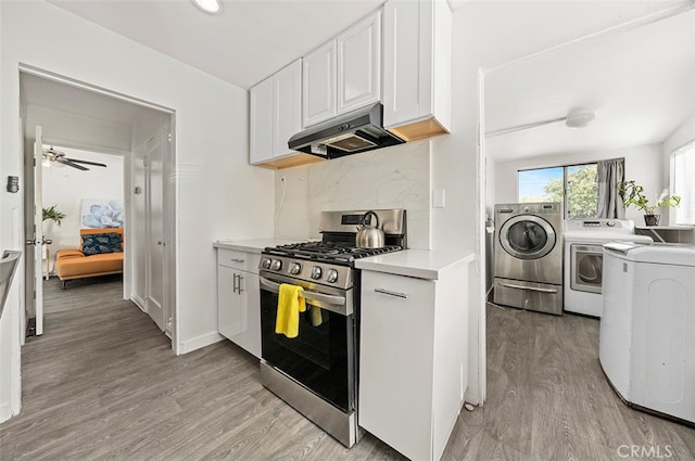 kitchen with light hardwood / wood-style floors, separate washer and dryer, white cabinetry, gas stove, and range hood