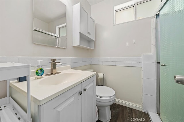 bathroom with hardwood / wood-style flooring, a shower with door, vanity, and toilet