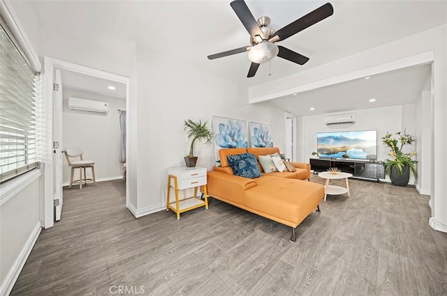 living room with a wall unit AC, hardwood / wood-style flooring, and ceiling fan