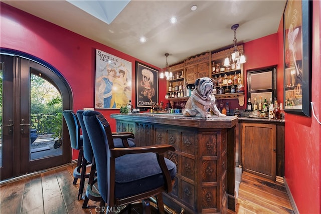 bar with wood-type flooring and pendant lighting