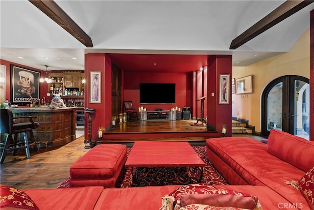 living room with french doors, beamed ceiling, bar, and hardwood / wood-style floors