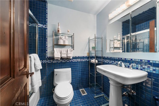 bathroom featuring tile walls, tile patterned floors, and toilet