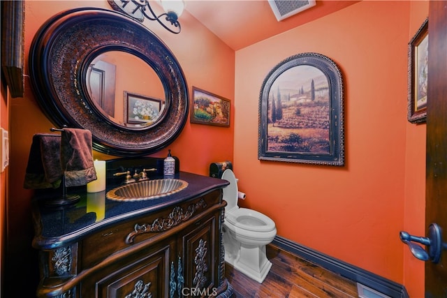 bathroom with toilet, vanity, and hardwood / wood-style flooring