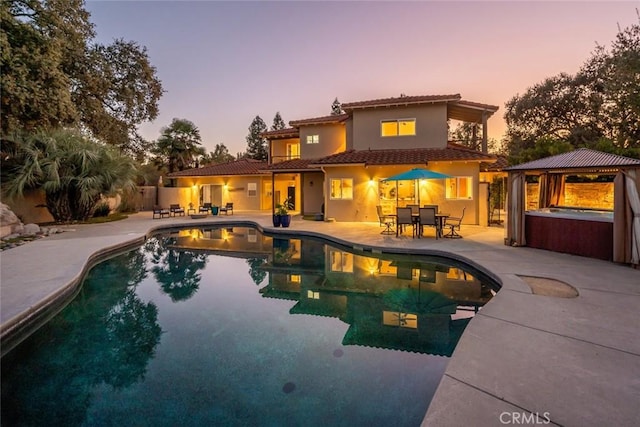 8865 San Gabriel Rd, Atascadero, CA 93422 - back of house at dusk with an outdoor hot tub, a patio area, a gazebo, a tiled roof, and an outdoor pool