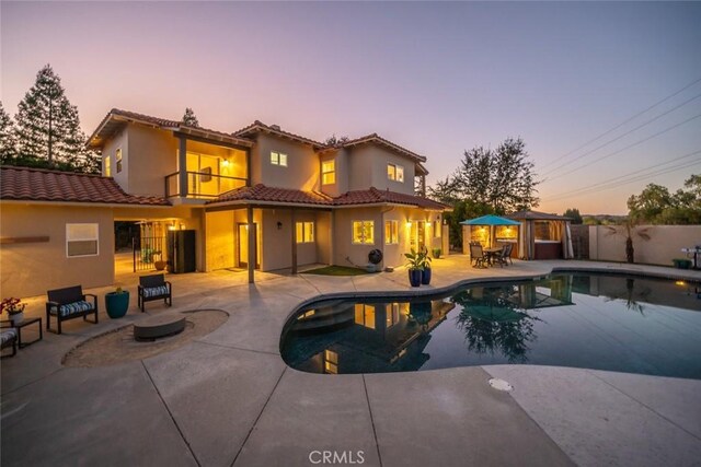 8865 San Gabriel Rd, Atascadero, CA 93422 - back of property at dusk featuring a balcony, a tile roof, a patio, stucco siding, and an outdoor fire pit