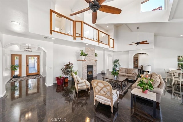 8865 San Gabriel Rd, Atascadero, CA 93422 - living area featuring ceiling fan, high vaulted ceiling, a stone fireplace, baseboards, and arched walkways