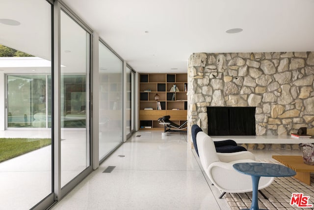 living room featuring a wall of windows and a stone fireplace