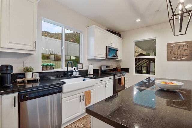 kitchen featuring sink, appliances with stainless steel finishes, white cabinetry, and dark stone counters