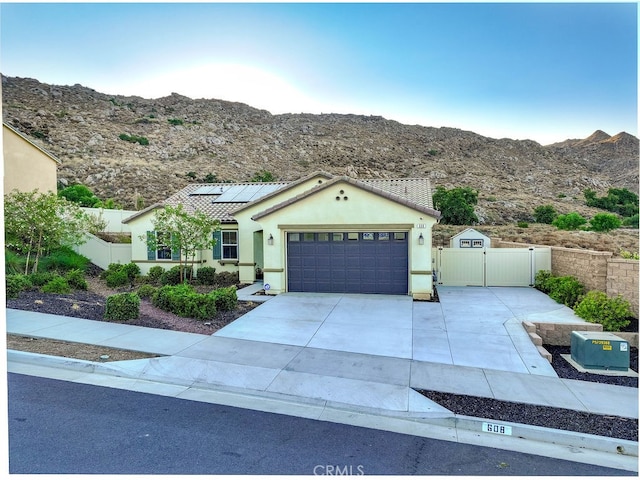 ranch-style home with a garage, a mountain view, and solar panels