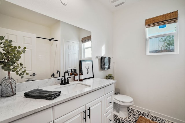 bathroom with vanity, toilet, a shower, and a wealth of natural light