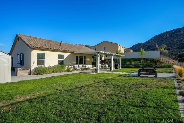 rear view of property featuring a patio, a mountain view, a yard, and a pergola