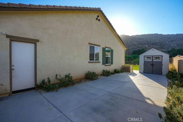 view of side of property featuring a storage unit, a mountain view, and a patio