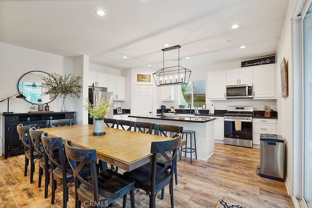 dining space with light hardwood / wood-style flooring, sink, and a notable chandelier