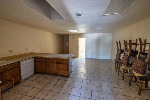 kitchen with kitchen peninsula, a textured ceiling, dishwasher, light tile patterned flooring, and sink