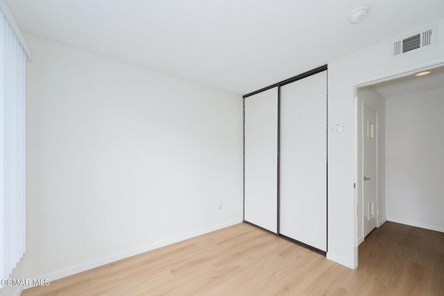 unfurnished bedroom with a closet and light hardwood / wood-style floors