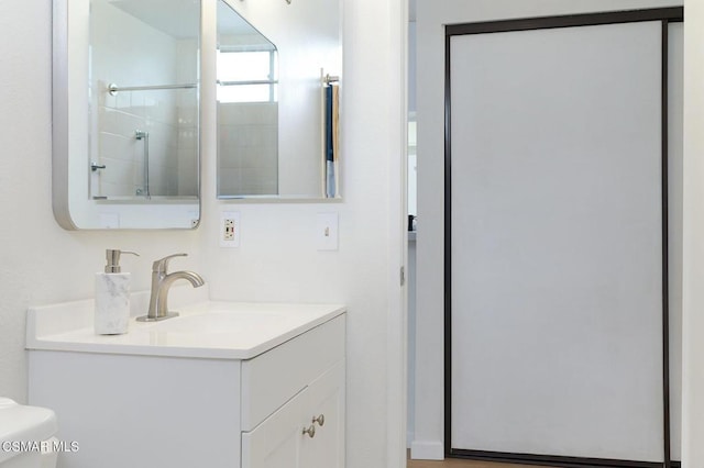 bathroom with toilet, a shower with door, and vanity