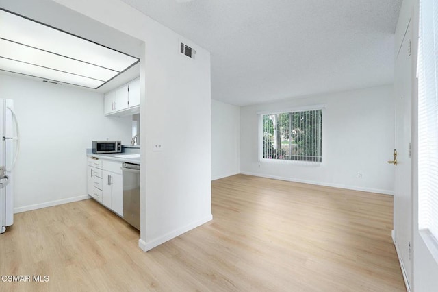 kitchen with white cabinets, stainless steel appliances, and light wood-type flooring