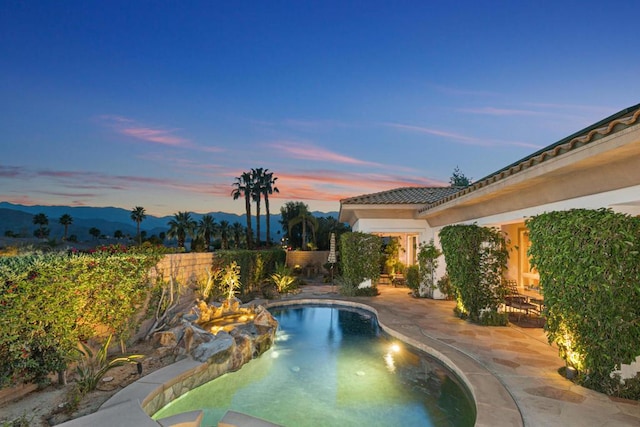 pool at dusk featuring a mountain view and a patio