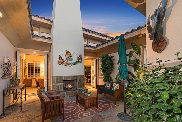 patio terrace at dusk featuring an outdoor living space with a fireplace