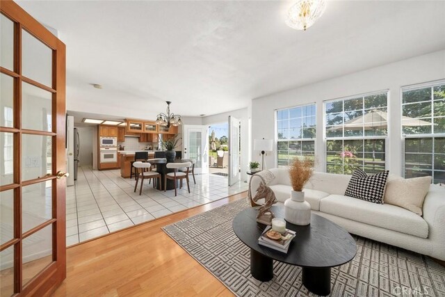 living room with french doors, light hardwood / wood-style flooring, and a notable chandelier