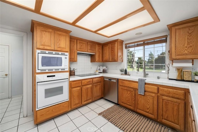 kitchen featuring tasteful backsplash, sink, light tile patterned floors, and white appliances