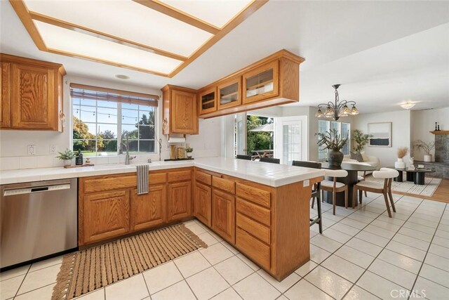 kitchen with kitchen peninsula, pendant lighting, a notable chandelier, dishwasher, and light tile patterned flooring