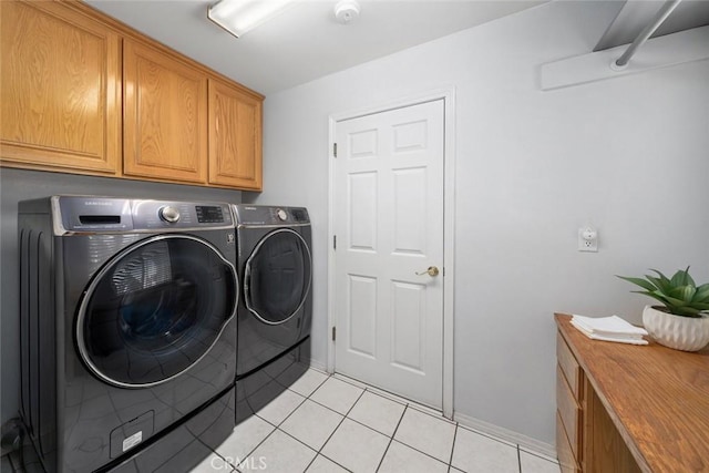 laundry area with light tile patterned flooring, cabinets, and independent washer and dryer