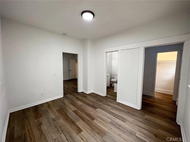 unfurnished bedroom featuring connected bathroom, dark hardwood / wood-style floors, and a closet